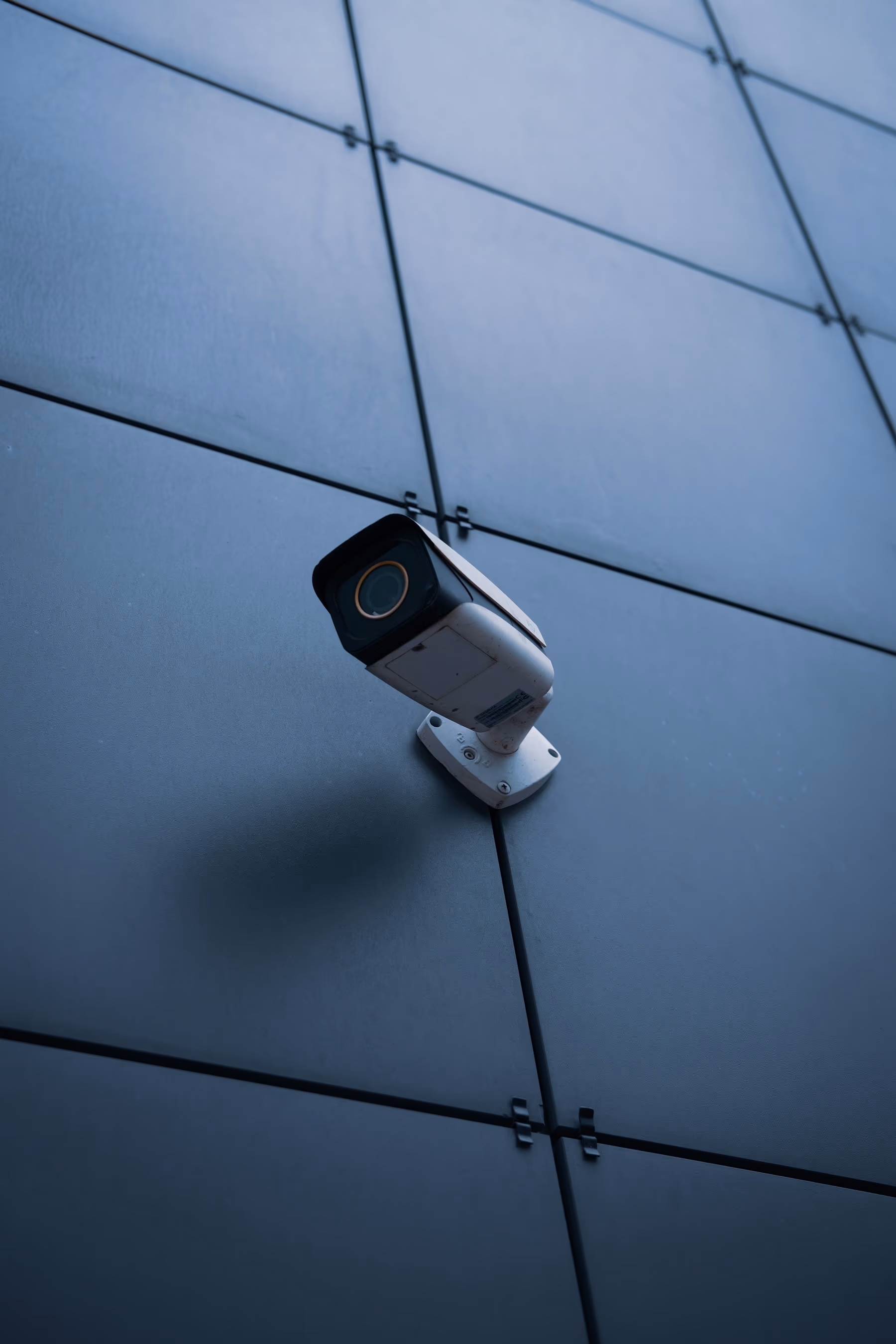 Cámara de videovigilancia tipo bala instalada en la fachada de un edificio, vista desde abajo